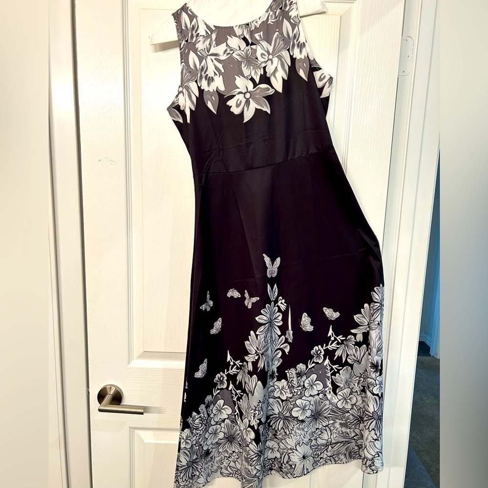 Sleeveless. Sleek, fitted black dress with white/grey floral design.
